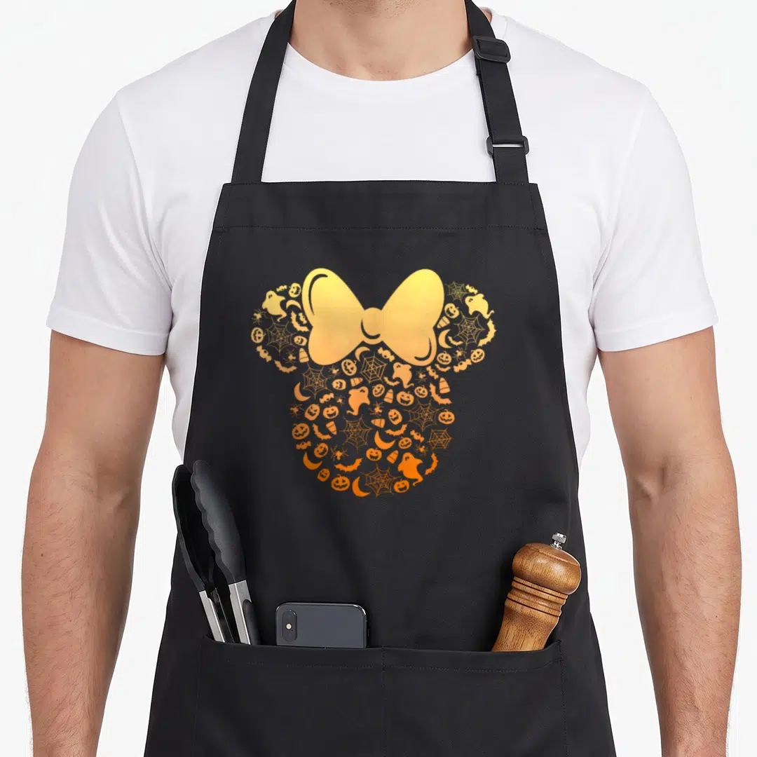 Ghost pumpkin apron - Yellow and orange bow surrounded by Halloween icons forming a head silhouette — shown on a black cotton canvas apron against a white background
