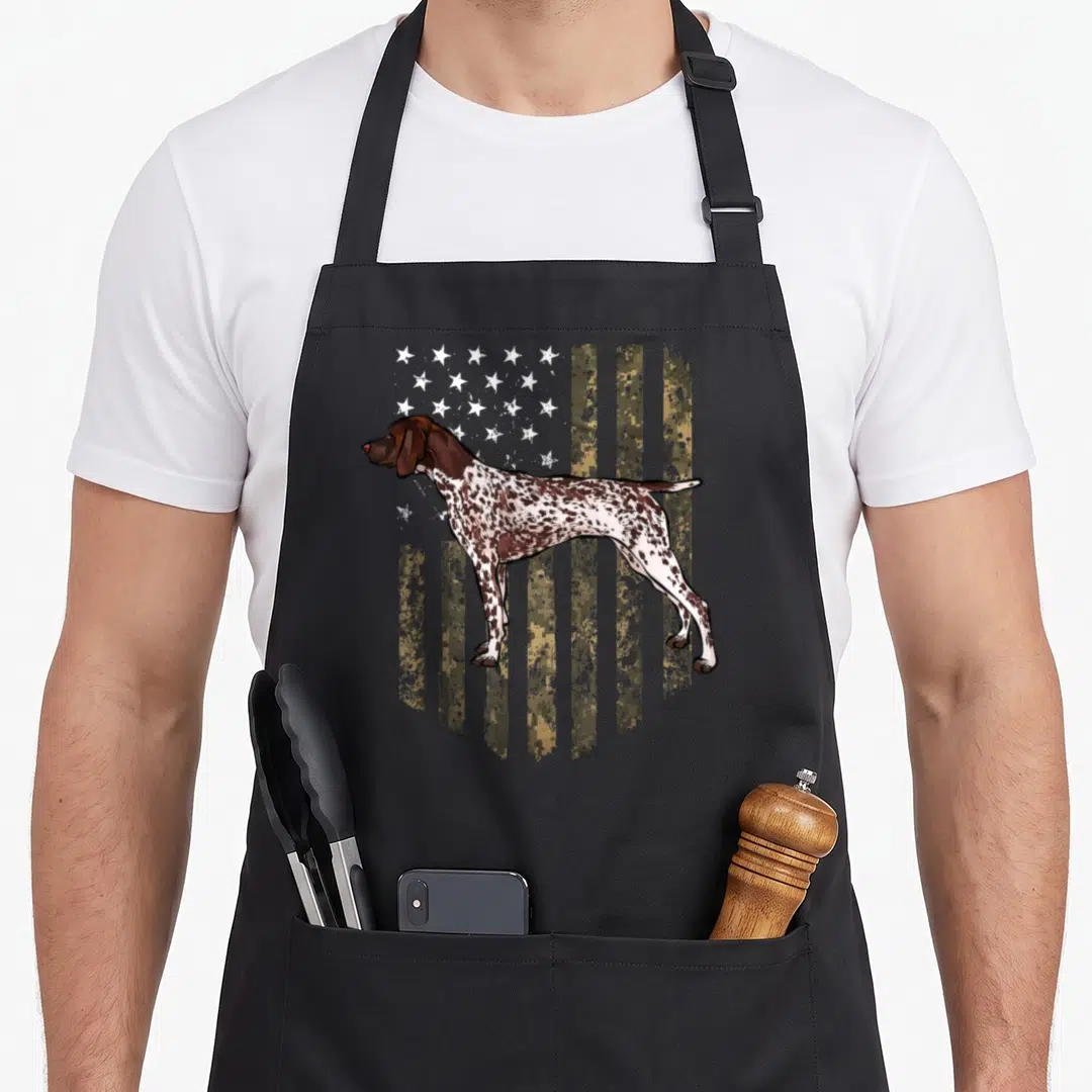 Camo 4th of july apron - Realistic brown and white dog standing before a digital camouflage American flag pattern — shown on a black cotton canvas apron against a white background