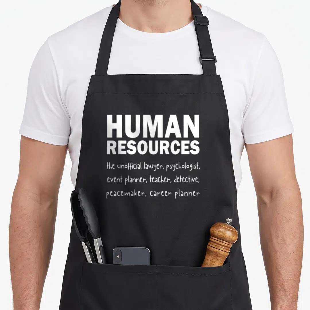 Definition hr apron - White text reading HUMAN RESOURCES the unofficial lawyer psychologist event planner teacher — shown on a black cotton canvas apron against a white background