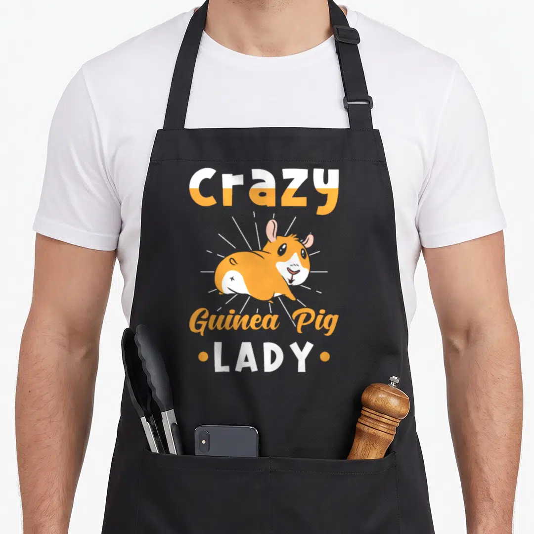 Pig animal crazy guinea lady apron - Orange and white cartoon guinea pig with Crazy Guinea Pig LADY text and radiating — shown on a black cotton canvas apron against a white background