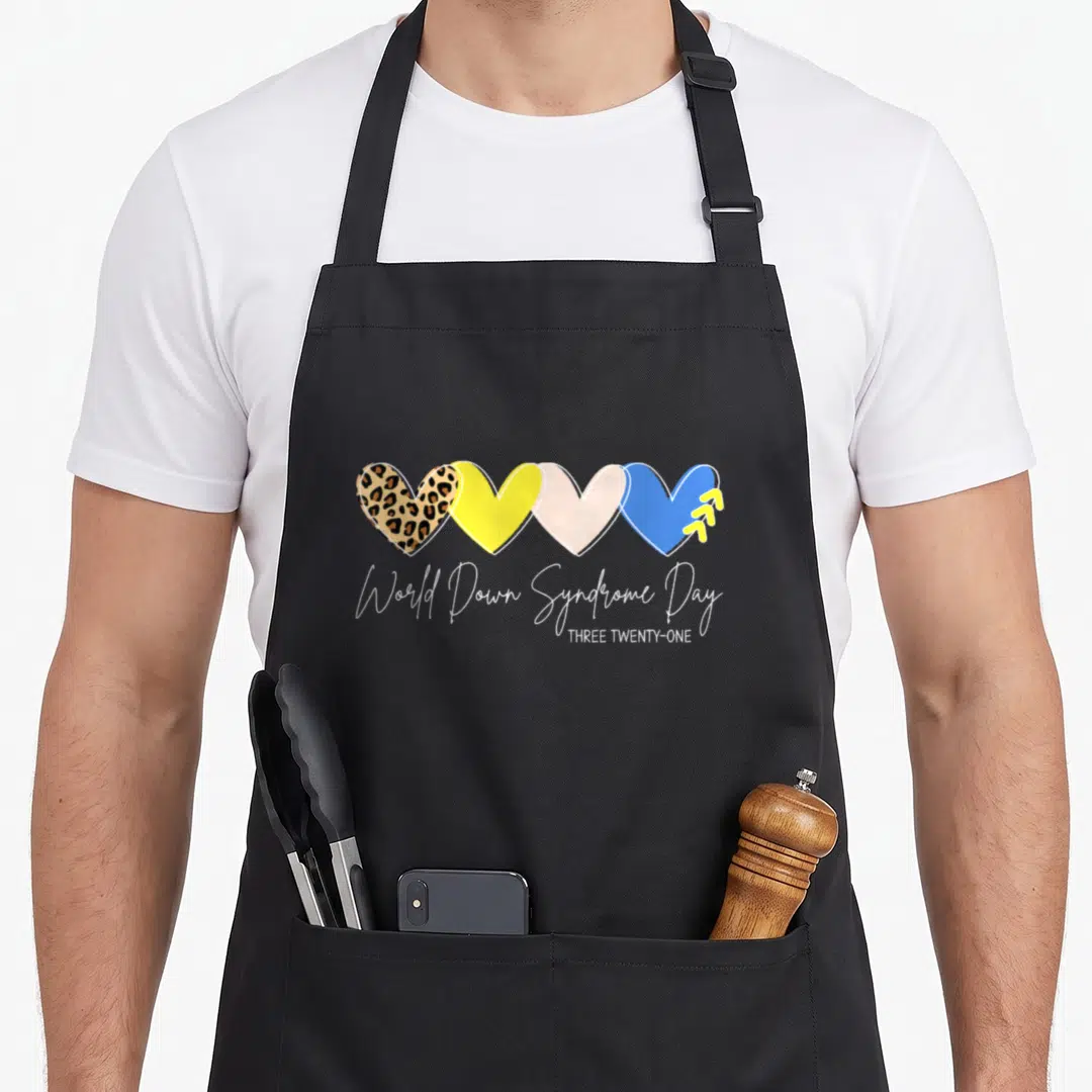 Trisomy down syndrome awareness apron - Four overlapping hearts in leopard, yellow, pink, and blue with white script — shown on a black cotton canvas apron against a white background