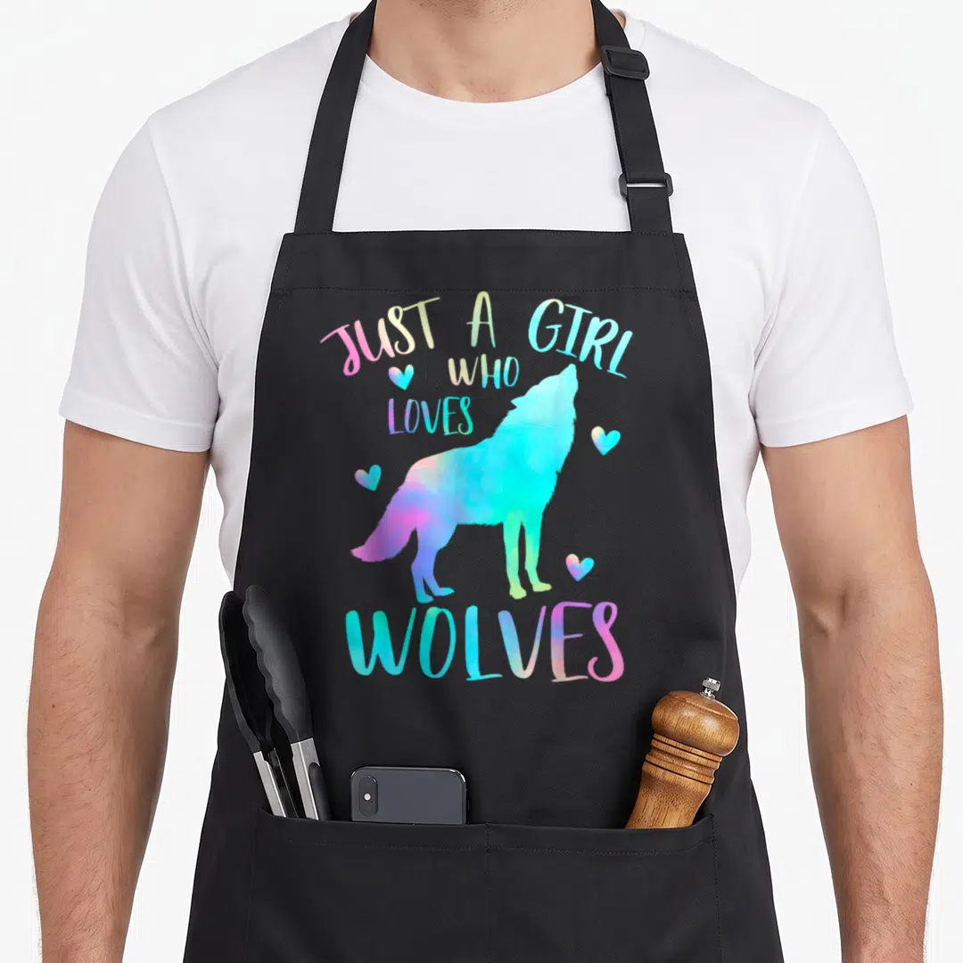 Watercolor wolves apron - Pastel watercolor howling wolf with four hearts and arched text reading Just A Girl Who Loves — shown on a black cotton canvas apron against a white background
