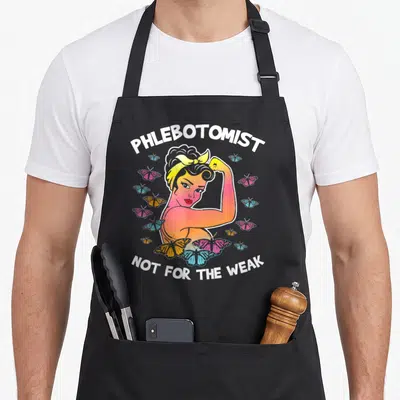 Phlebotomist butterfly apron - Cartoon woman flexing arm surrounded by pink, blue, orange butterflies with white text — shown on a black cotton canvas apron against a white background