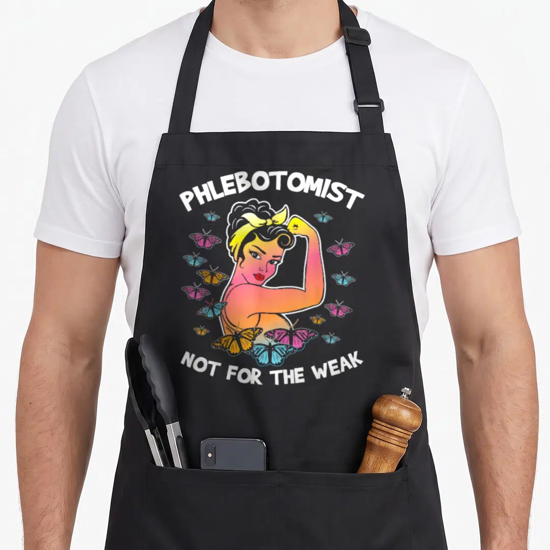 Phlebotomist butterfly apron - Cartoon woman flexing arm surrounded by pink, blue, orange butterflies with white text — shown on a black cotton canvas apron against a white background