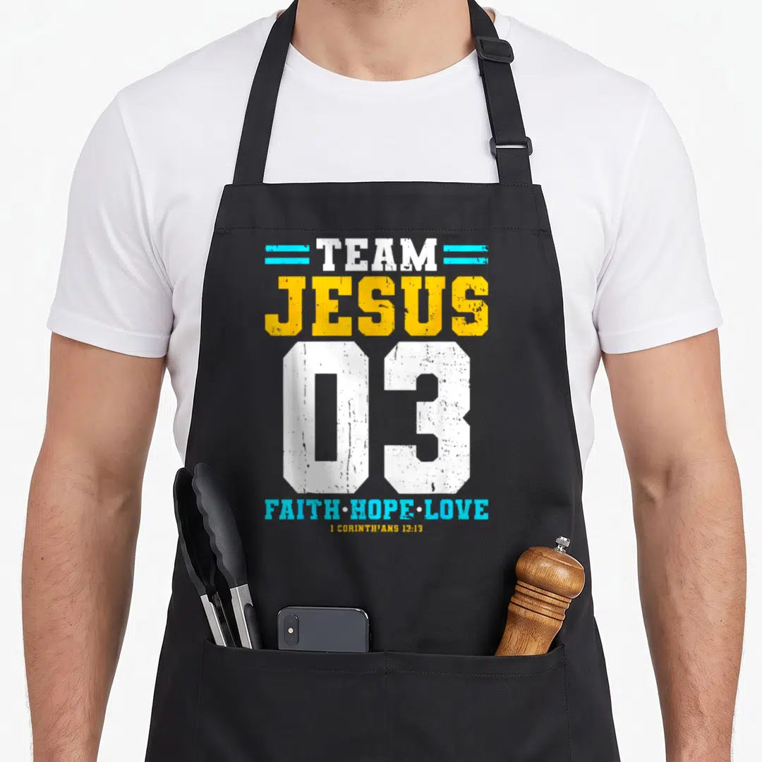 Jesus faith christian apron - Team Jesus 03 text design with Faith Hope Love in white yellow and blue — shown on a black cotton canvas apron against a white background