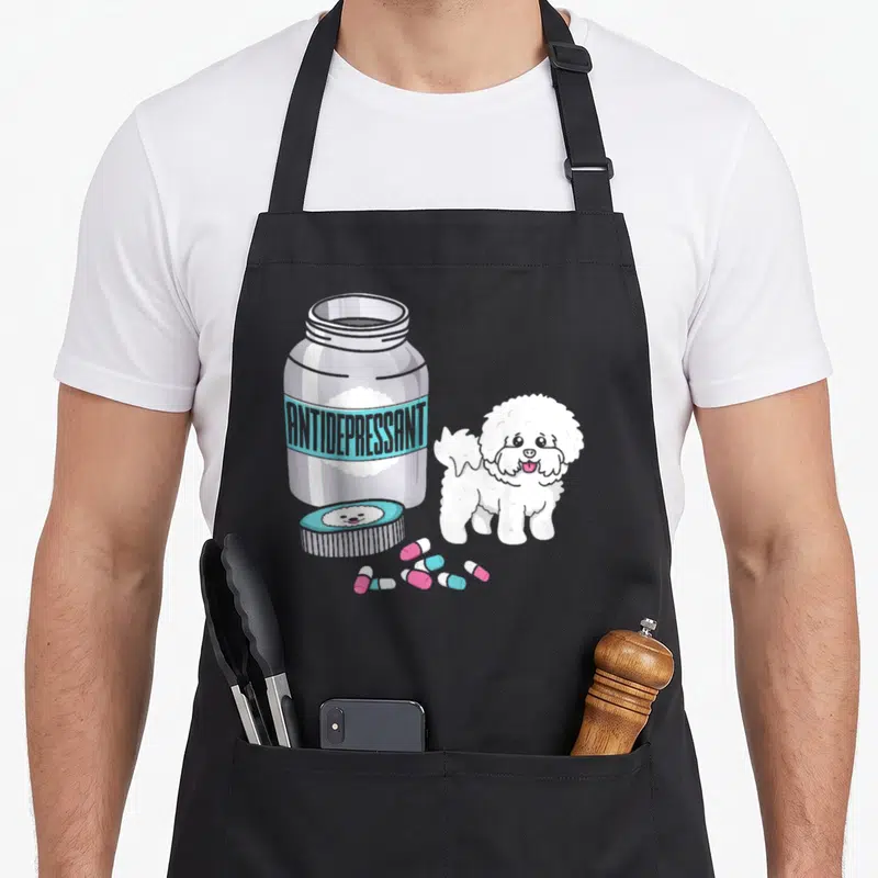 Frise antidepressant dog apron - Cartoon silver pill bottle with blue label and white Bichon Frise dog with pink — shown on a black cotton canvas apron against a white background