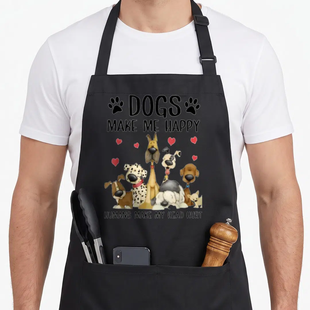 Human dog apron - Six cartoon dogs with red hearts and text DOGS MAKE ME HAPPY HUMANS MAKE MY HEAD HURT — shown on a black cotton canvas apron against a white background