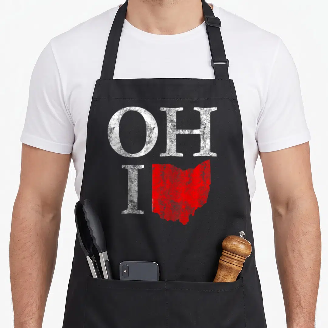 Ohio cutecomfy apron - Distressed white OHIO text with red Ohio state map shape replacing the bottom right letter — shown on a black cotton canvas apron against a white background