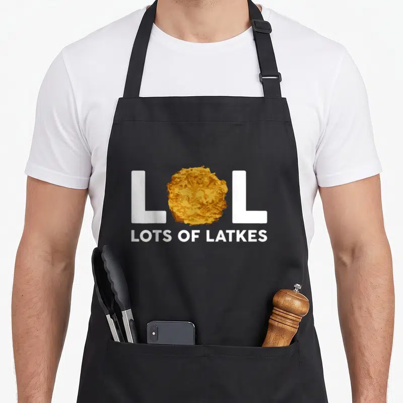 Lol hanukkah apron - Latke graphic replaces O in white LOL text above LOTS OF LATKES slogan — shown on a black cotton canvas apron against a white background
