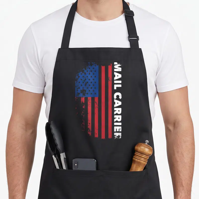 Mail patriotic apron - Vertical distressed USA flag with MAIL CARRIER text along right edge in red white blue — shown on a black cotton canvas apron against a white background