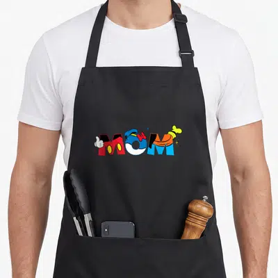 Funny friend mother's day aprons - MOM text with glove bow and arm in red blue yellow white cartoon style — shown on a black cotton canvas apron against a white background