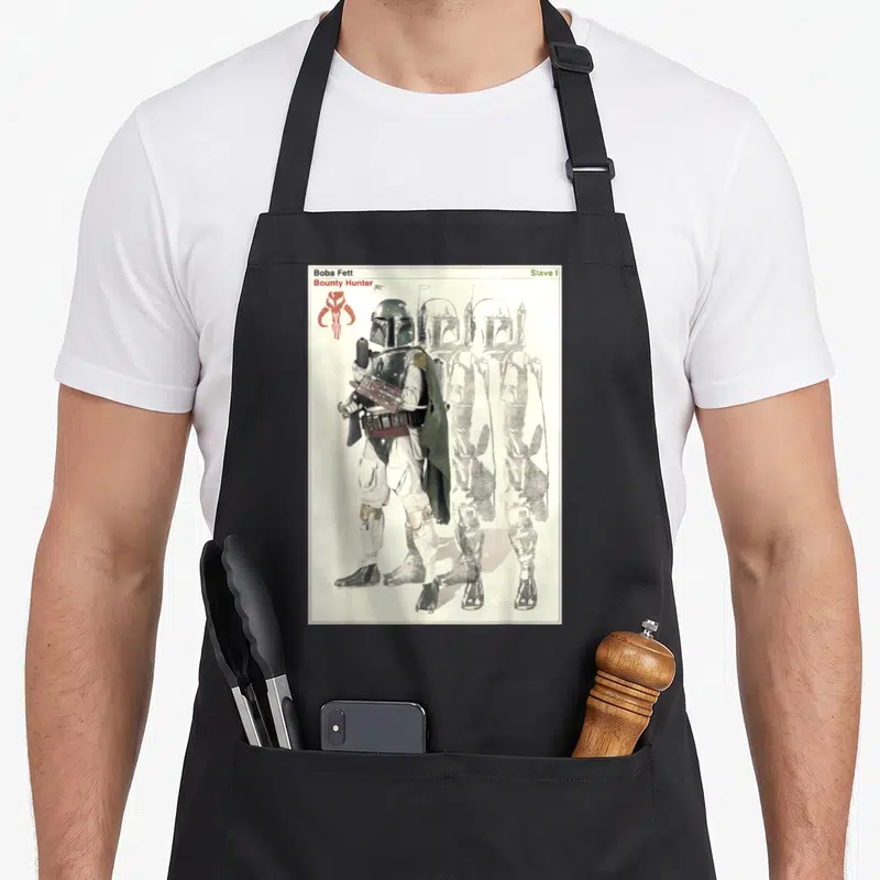Poster hunter apron - Boba Fett standing with two faded sketches and text reading Slave I and Bounty Hunter — shown on a black cotton canvas apron against a white background