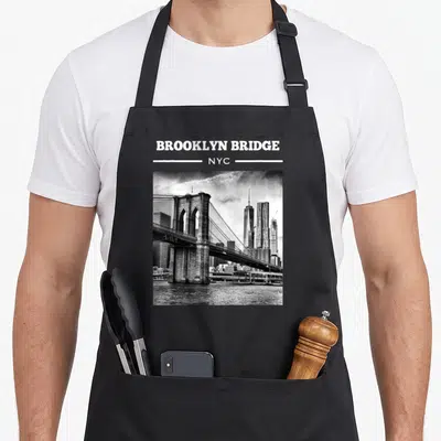 Bridge nyc new york apron - BROOKLYN BRIDGE NYC text above square black and white bridge photo — shown on a black cotton canvas apron against a white background
