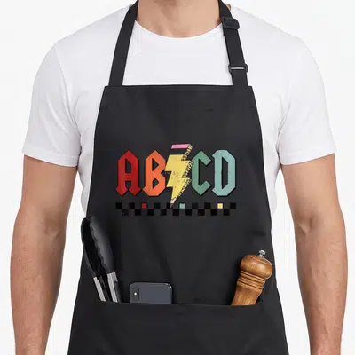 Rock preschool teacher apron - ABCD letters with lightning bolt pencil and checkerboard squares in retro colors — shown on a black cotton canvas apron against a white background