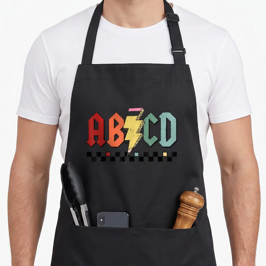 Rock preschool teacher apron - ABCD letters with lightning bolt pencil and checkerboard squares in retro colors — shown on a black cotton canvas apron against a white background