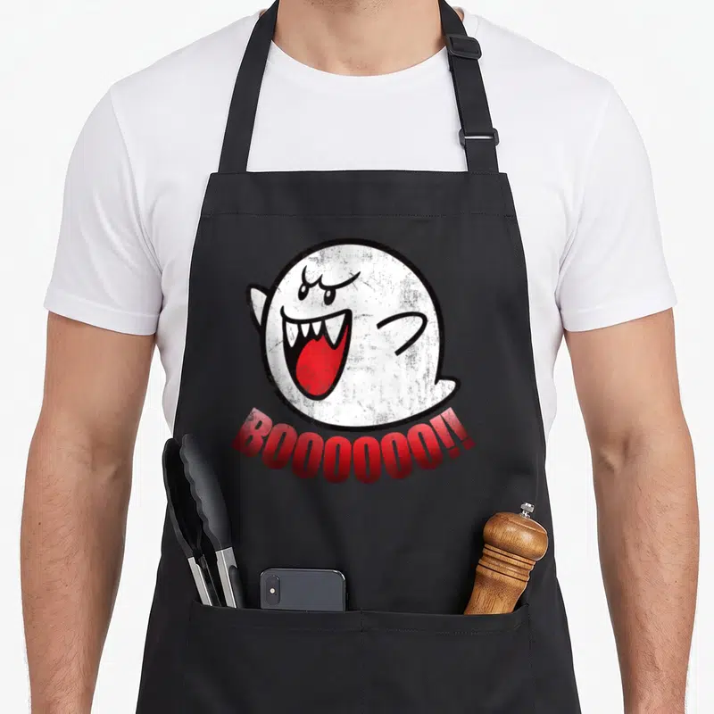 Boo panic attack apron - White cartoon ghost with red tongue and curved BOOOOOO!! text on black background — shown on a black cotton canvas apron against a white background