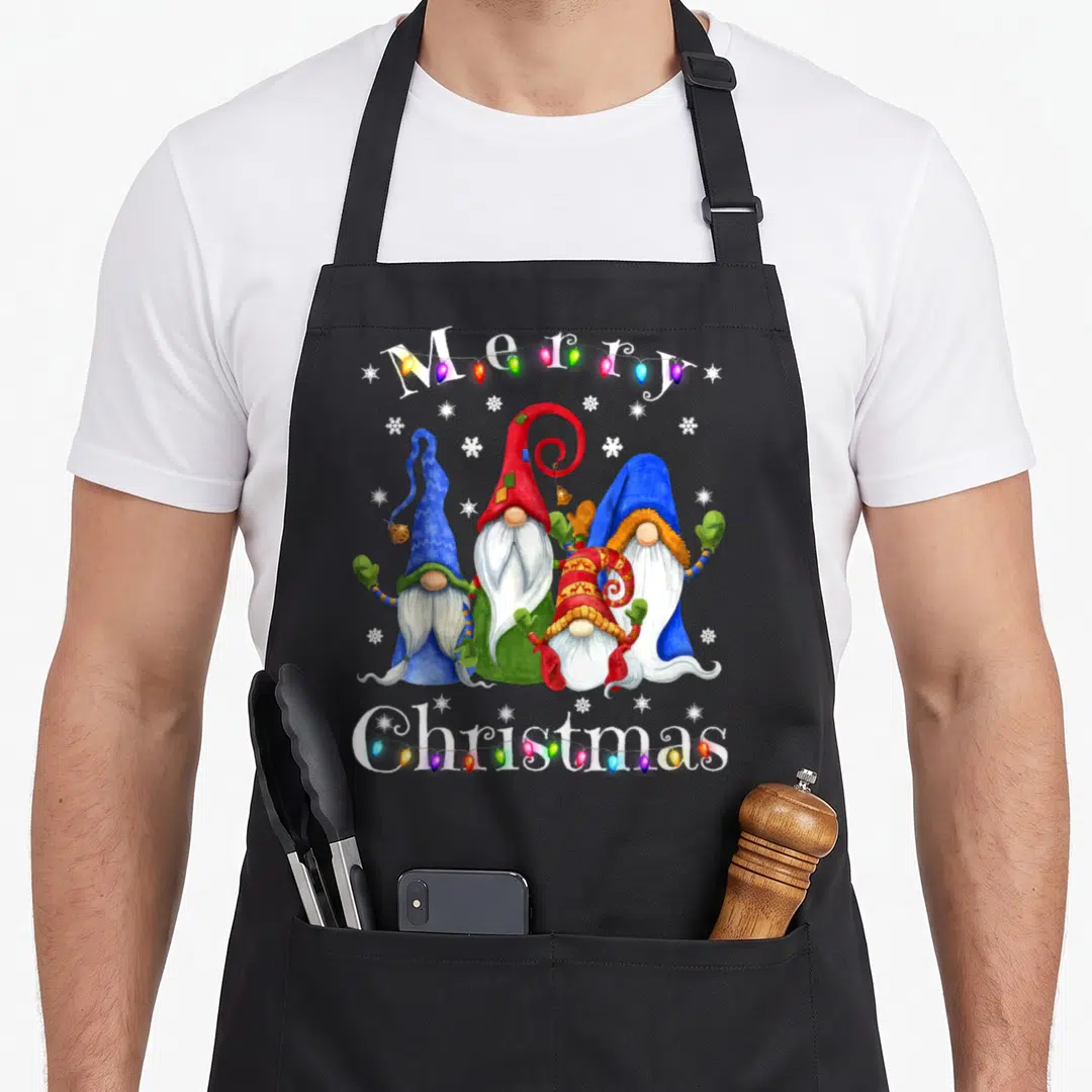 Pajamas merry christmas apron - Four gnomes and multicolored lights with Merry Christmas text in watercolor style — shown on a black cotton canvas apron against a white background