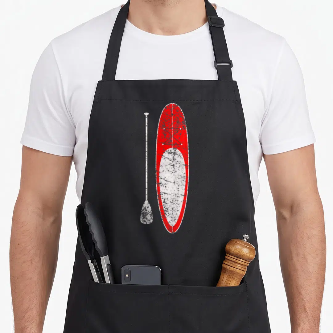 Paddling stand up paddle apron - Red and white distressed stand up paddleboard with white paddle standing vertically — shown on a black cotton canvas apron against a white background