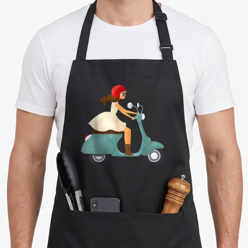 Funny scooter apron - Cartoon woman in cream dress and red helmet riding light blue scooter facing right — shown on a black cotton canvas apron against a white background