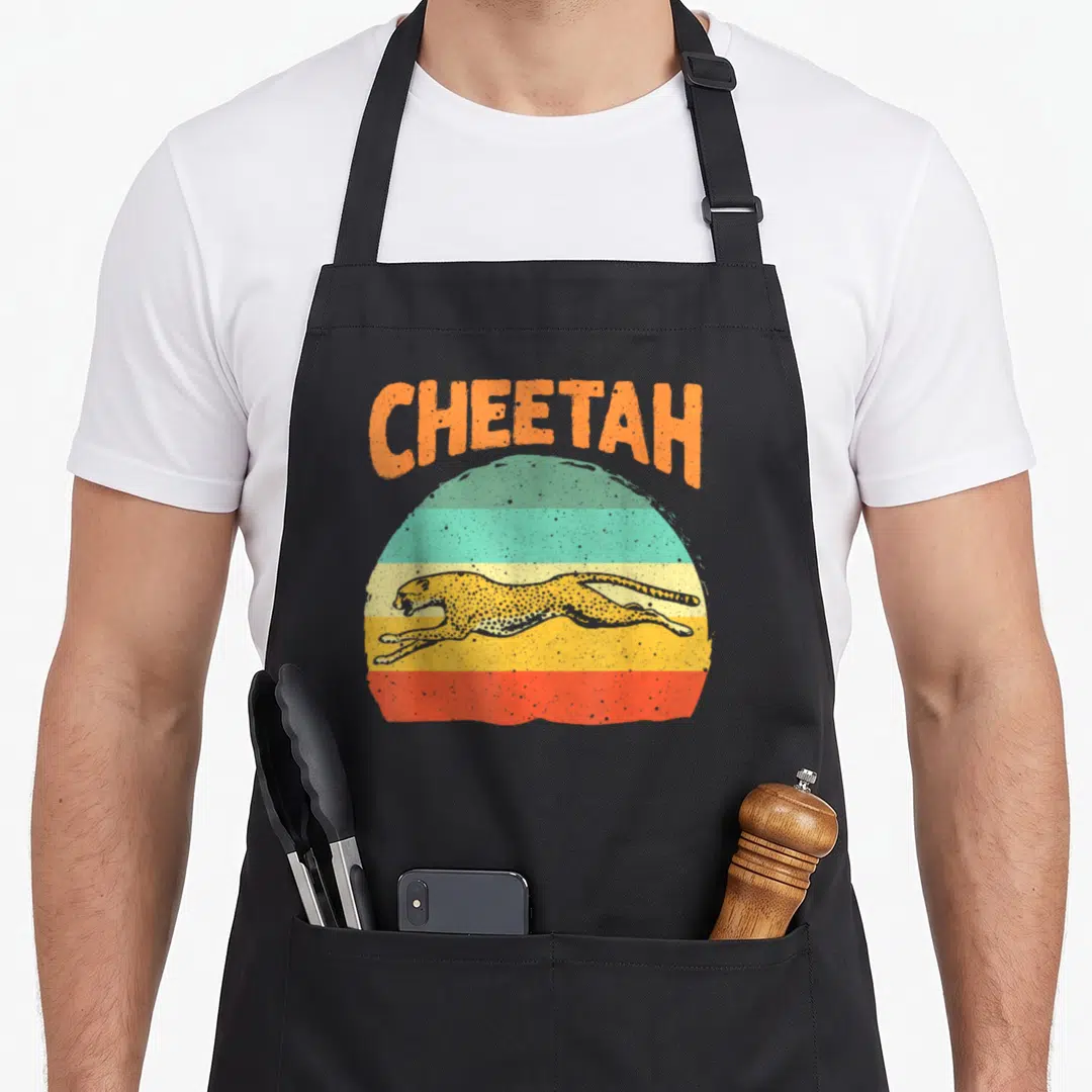 Leopard safari cheetah apron - Arched orange CHEETAH text above leaping cat on striped teal yellow and green retro — shown on a black cotton canvas apron against a white background