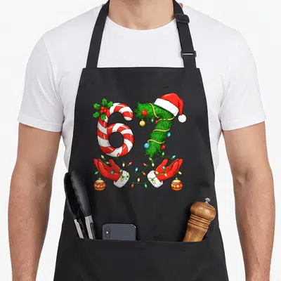 Trending christmas santa apron - Number 67 formed by candy cane and pine branch with gloved hands holding Christmas — shown on a black cotton canvas apron against a white background