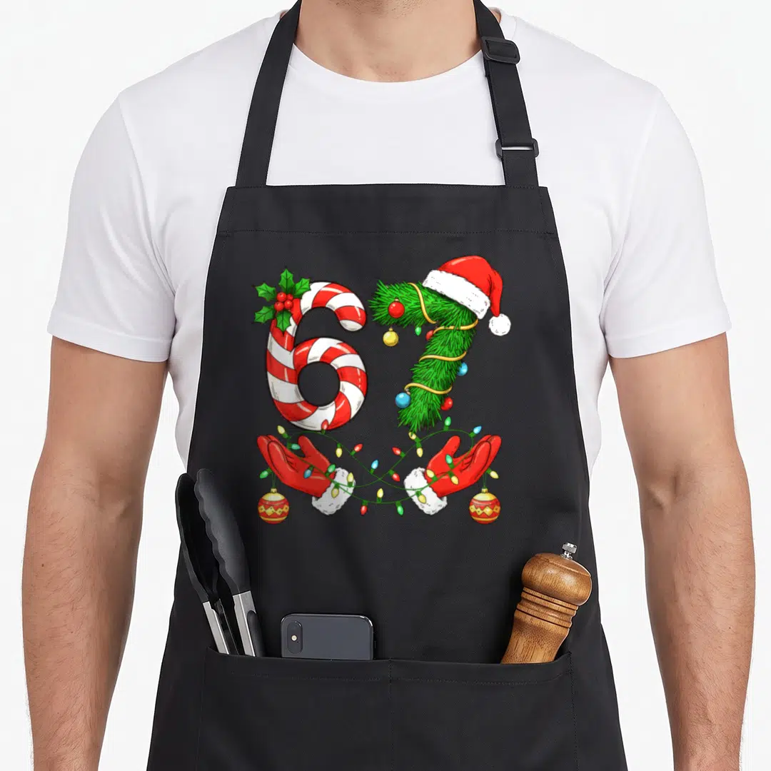 Trending christmas santa apron - Number 67 formed by candy cane and pine branch with gloved hands holding Christmas — shown on a black cotton canvas apron against a white background