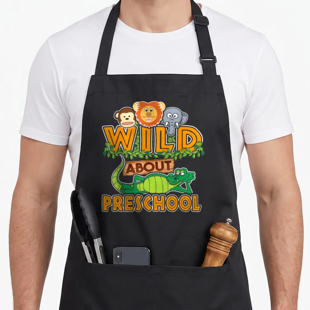 Preschool classroom aprons - Cartoon monkey lion elephant crocodile with Wild About Preschool text and leaves — shown on a black cotton canvas apron against a white background