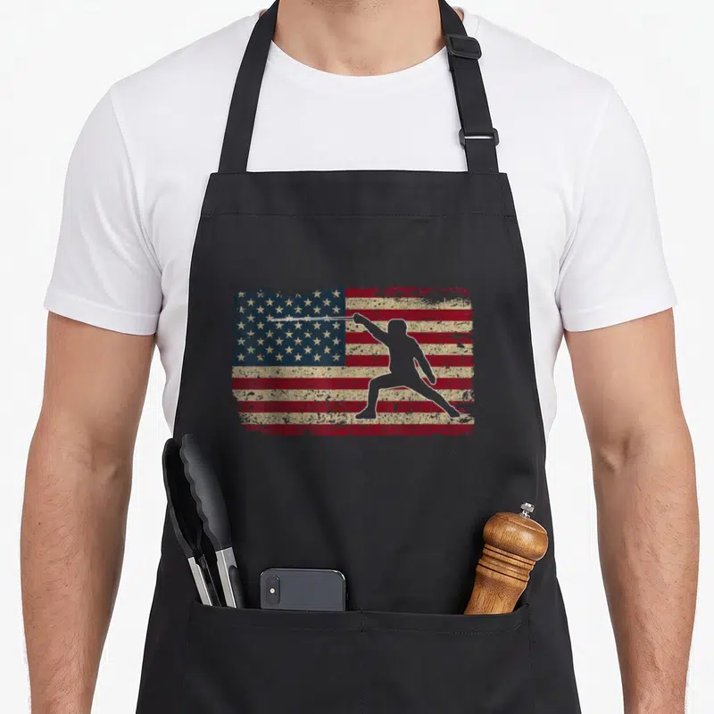 Flag fencing apron - Distressed USA flag with white fencer silhouette extending sword arm — shown on a black cotton canvas apron against a white background