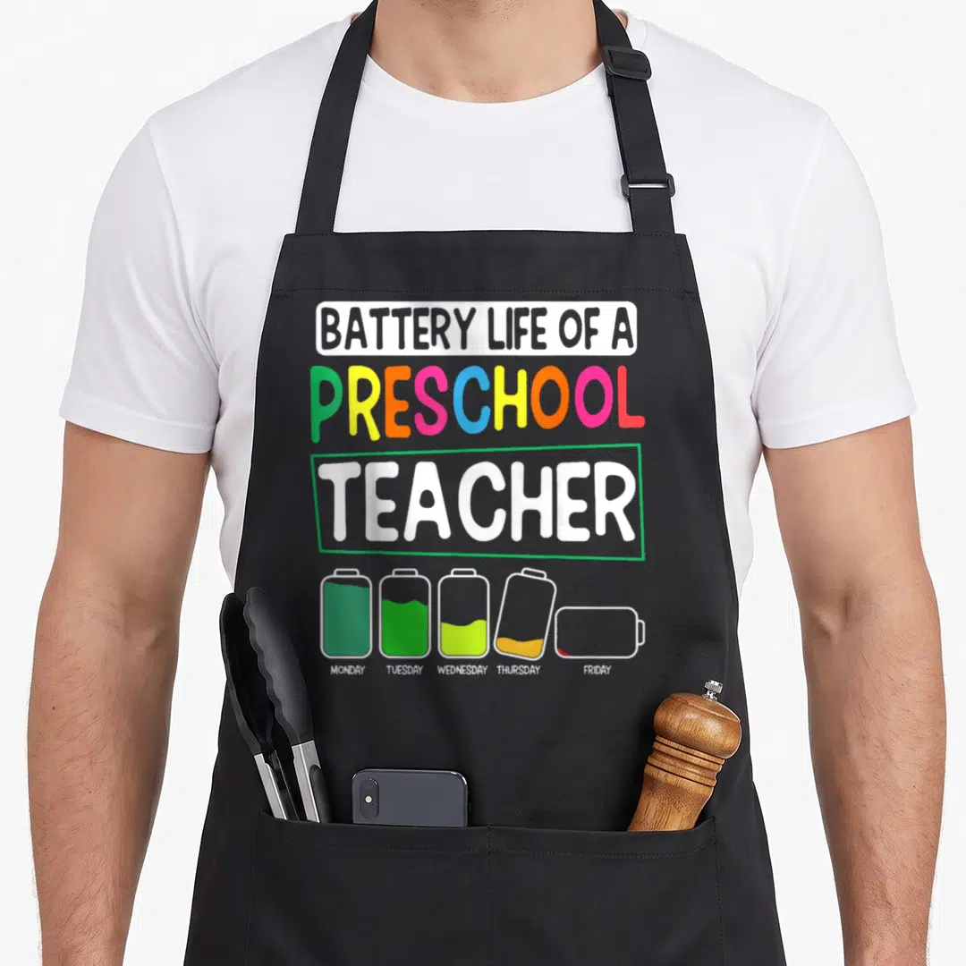 Nursery preschool teacher apron - Five battery icons showing declining charge from Monday to Friday under multicolored — shown on a black cotton canvas apron against a white background