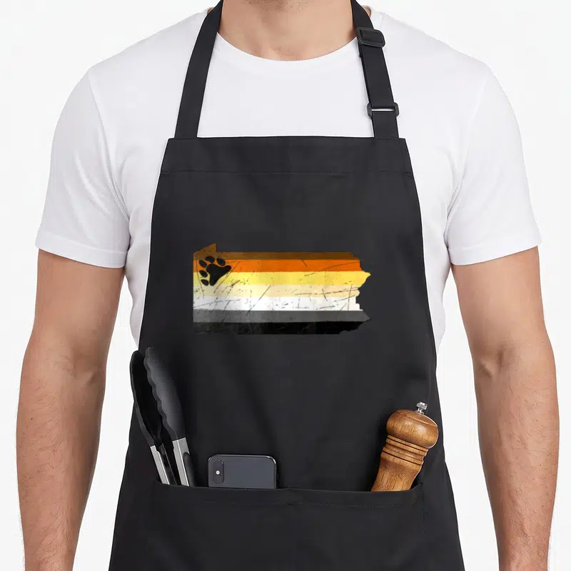 Pennsylvania bear apron - Distressed PA map with 5 colored stripes and black bear paw print on left — shown on a black cotton canvas apron against a white background