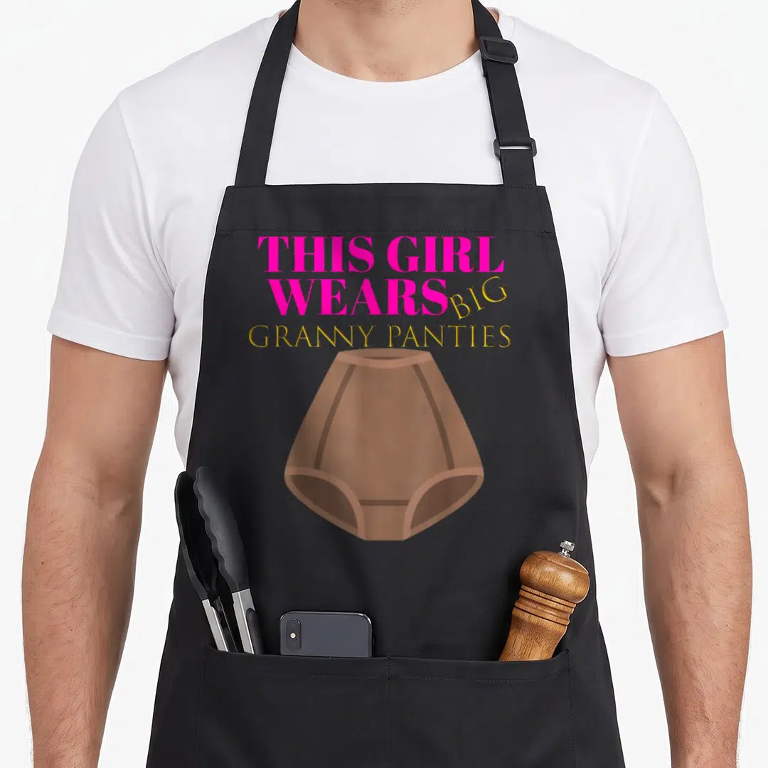 Panty granny apron - Pink and gold text reading THIS GIRL WEARS BIG GRANNY PANTIES above a brown high-waisted — shown on a black cotton canvas apron against a white background