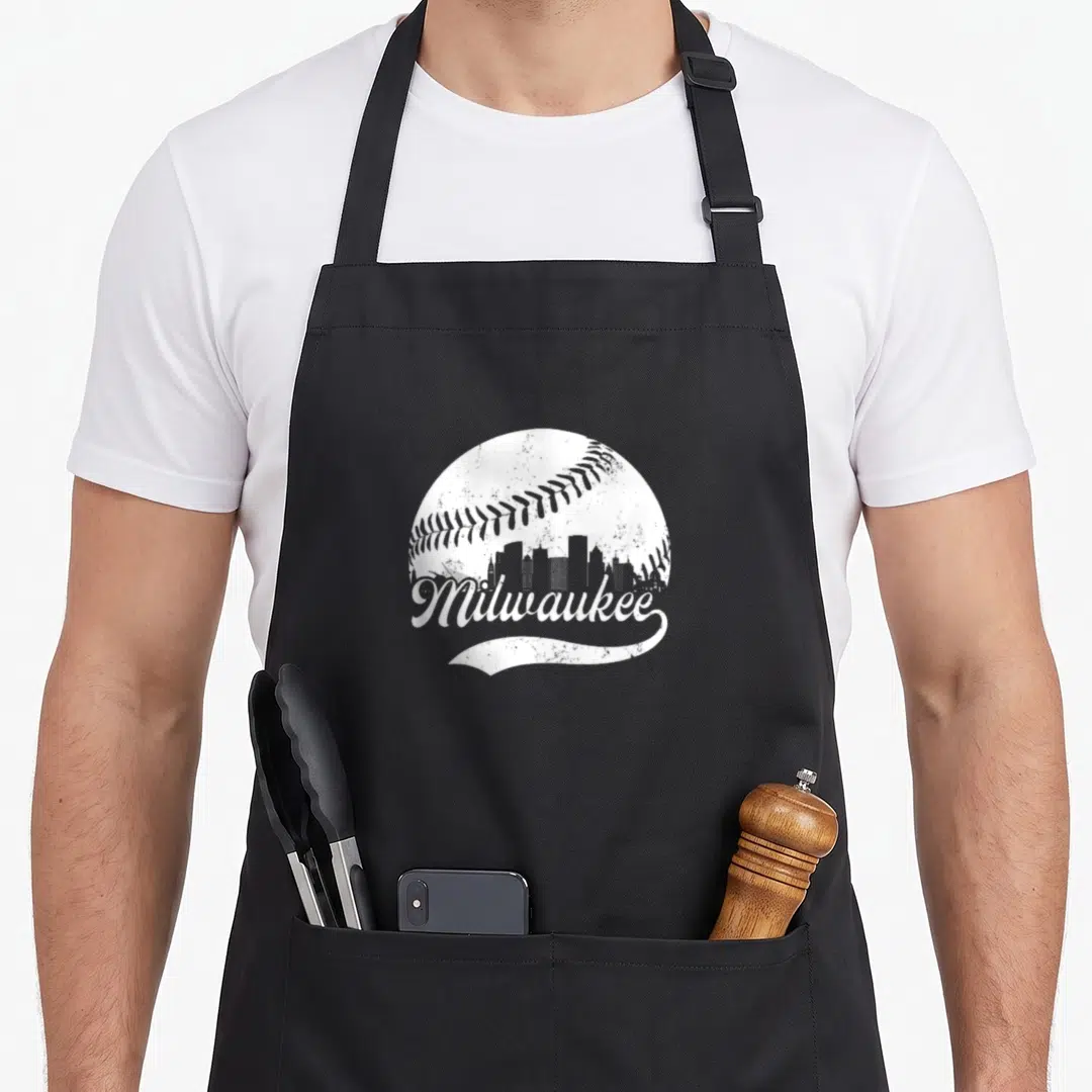 Wisconsin skyline milwaukee apron - White distressed baseball silhouette containing a dark city skyline and script — shown on a black cotton canvas apron against a white background