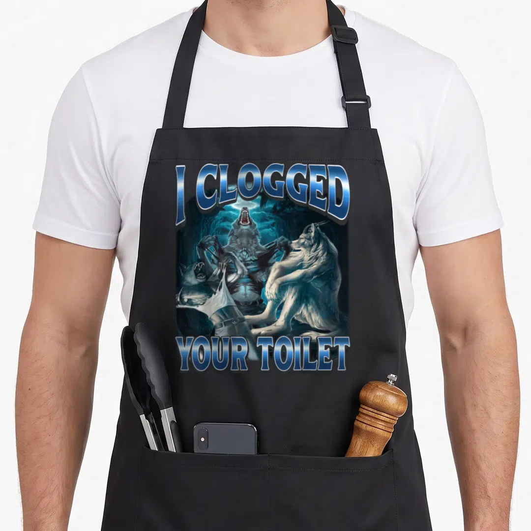 Clogged alpha apron - I Clogged Your Toilet text with three werewolves shredding paper in blue and grey — shown on a black cotton canvas apron against a white background