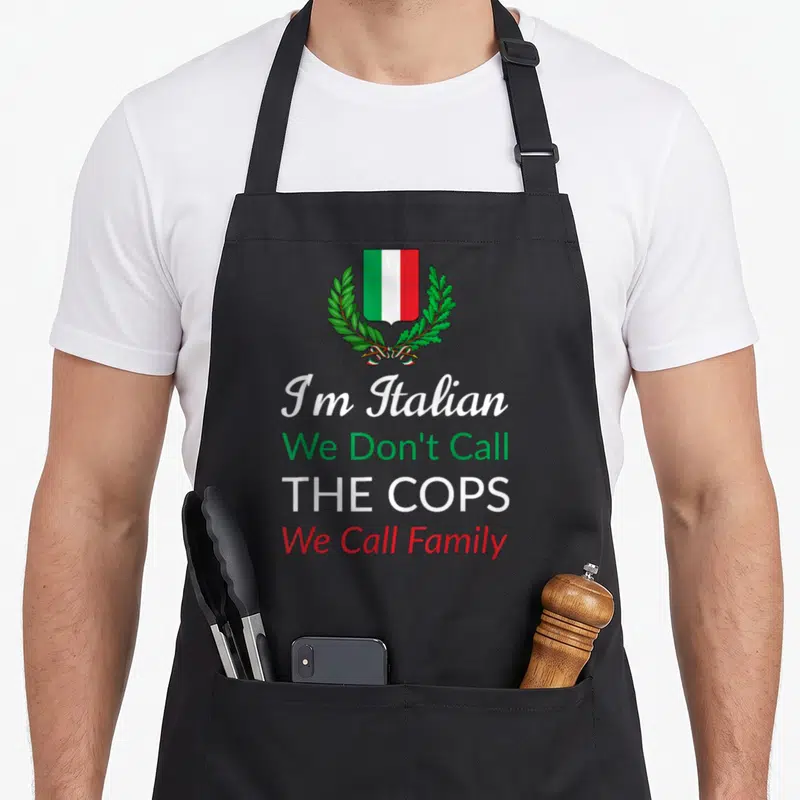 Call italy apron - Shield with green white red stripes and laurel wreath above four lines of text — shown on a black cotton canvas apron against a white background
