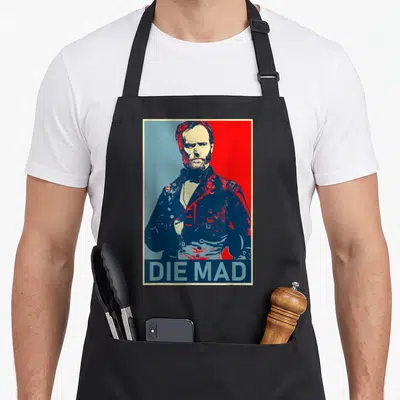 Die mad apron - Retro portrait of a bearded man in a military jacket above the text DIE MAD on a split blue and red — shown on a black cotton canvas apron against a white background