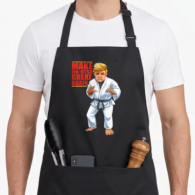 Bjj jiu apron - Donald Trump in white gi with black belt beside red text Make Jiu-Jitsu Great Again — shown on a black cotton canvas apron against a white background