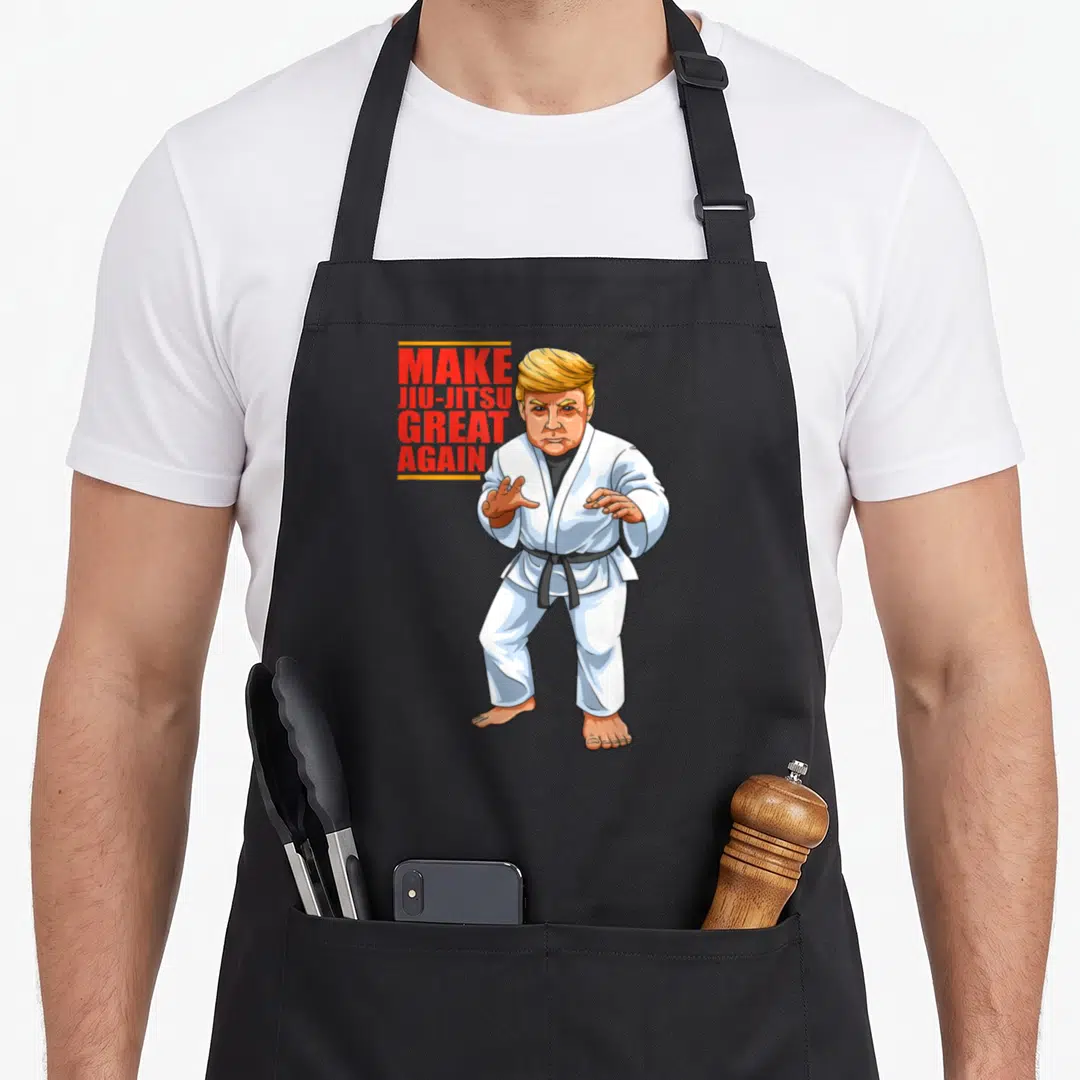 Bjj jiu apron - Donald Trump in white gi with black belt beside red text Make Jiu-Jitsu Great Again — shown on a black cotton canvas apron against a white background
