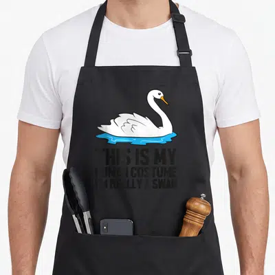 Human im swan apron - Cartoon white swan floating on blue water above three lines of black text reading This Is My — shown on a black cotton canvas apron against a white background