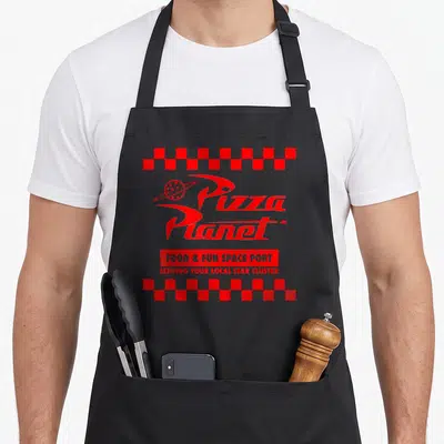 Checkered pizza planet apron - Red Pizza Planet logo with Food & Fun Space Port text and checkered borders — shown on a black cotton canvas apron against a white background