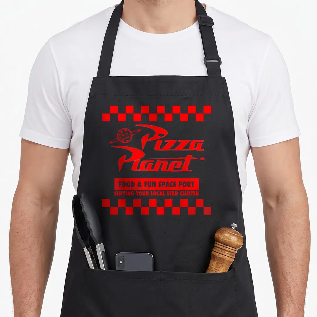 Checkered pizza planet apron - Red Pizza Planet logo with Food & Fun Space Port text and checkered borders — shown on a black cotton canvas apron against a white background