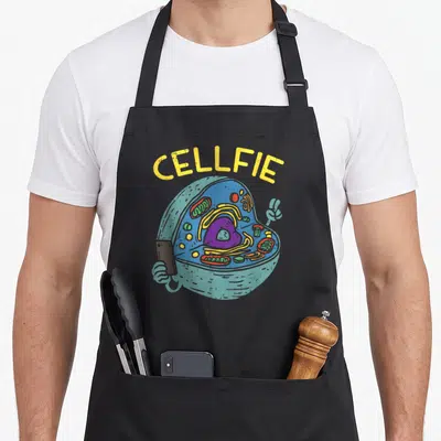 Cell teacher apron - Yellow CELLFIE text above cartoon cell holding phone making peace sign — shown on a black cotton canvas apron against a white background