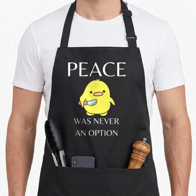 Dark meme apron - Yellow cartoon duck holding a knife with text PEACE WAS NEVER AN OPTION — shown on a black cotton canvas apron against a white background