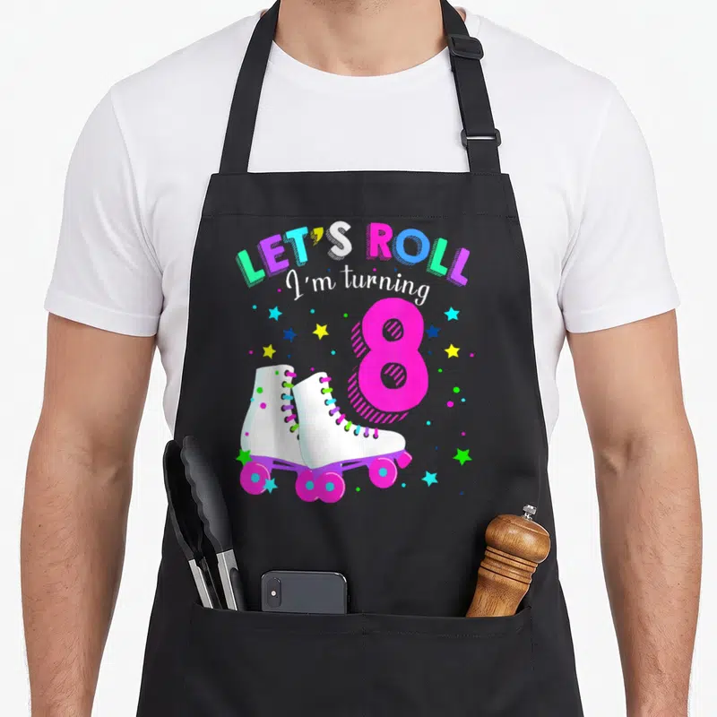 Skate rolling turning apron - White roller skates with pink 8 and LET'S ROLL I'm turning 8 text surrounded by stars — shown on a black cotton canvas apron against a white background