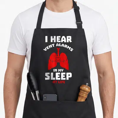 Hear asthma awareness apron - Red cartoon lungs with heartbeat line and white text I HEAR VENT ALARMS IN MY SLEEP — shown on a black cotton canvas apron against a white background