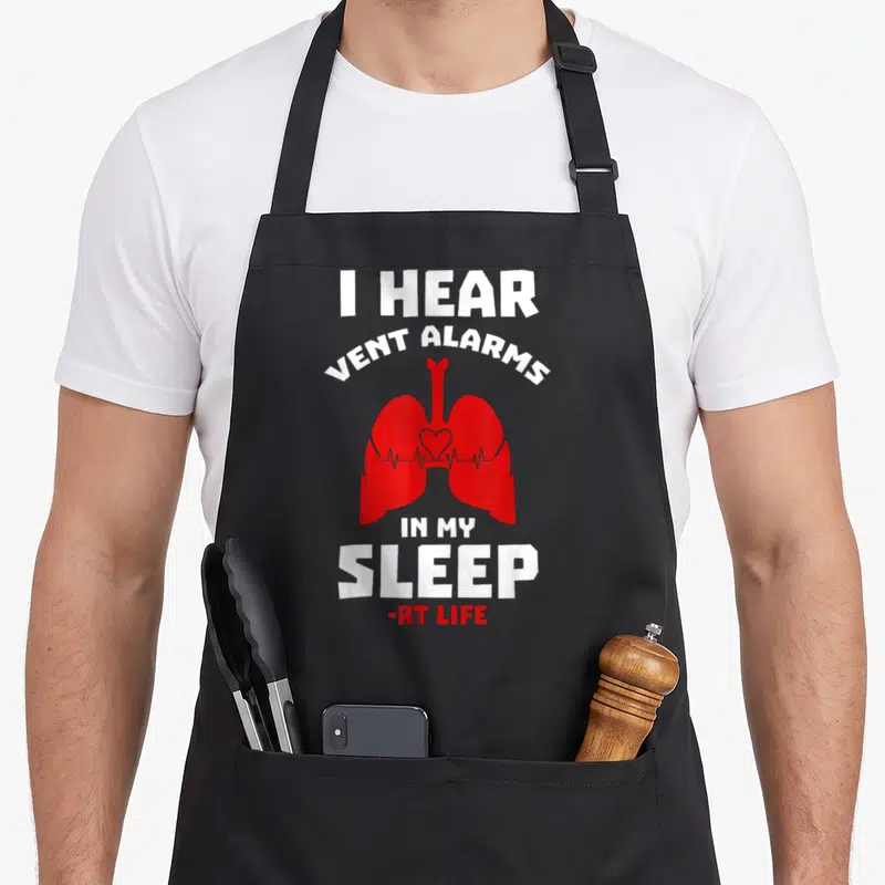 Hear asthma awareness apron - Red cartoon lungs with heartbeat line and white text I HEAR VENT ALARMS IN MY SLEEP — shown on a black cotton canvas apron against a white background