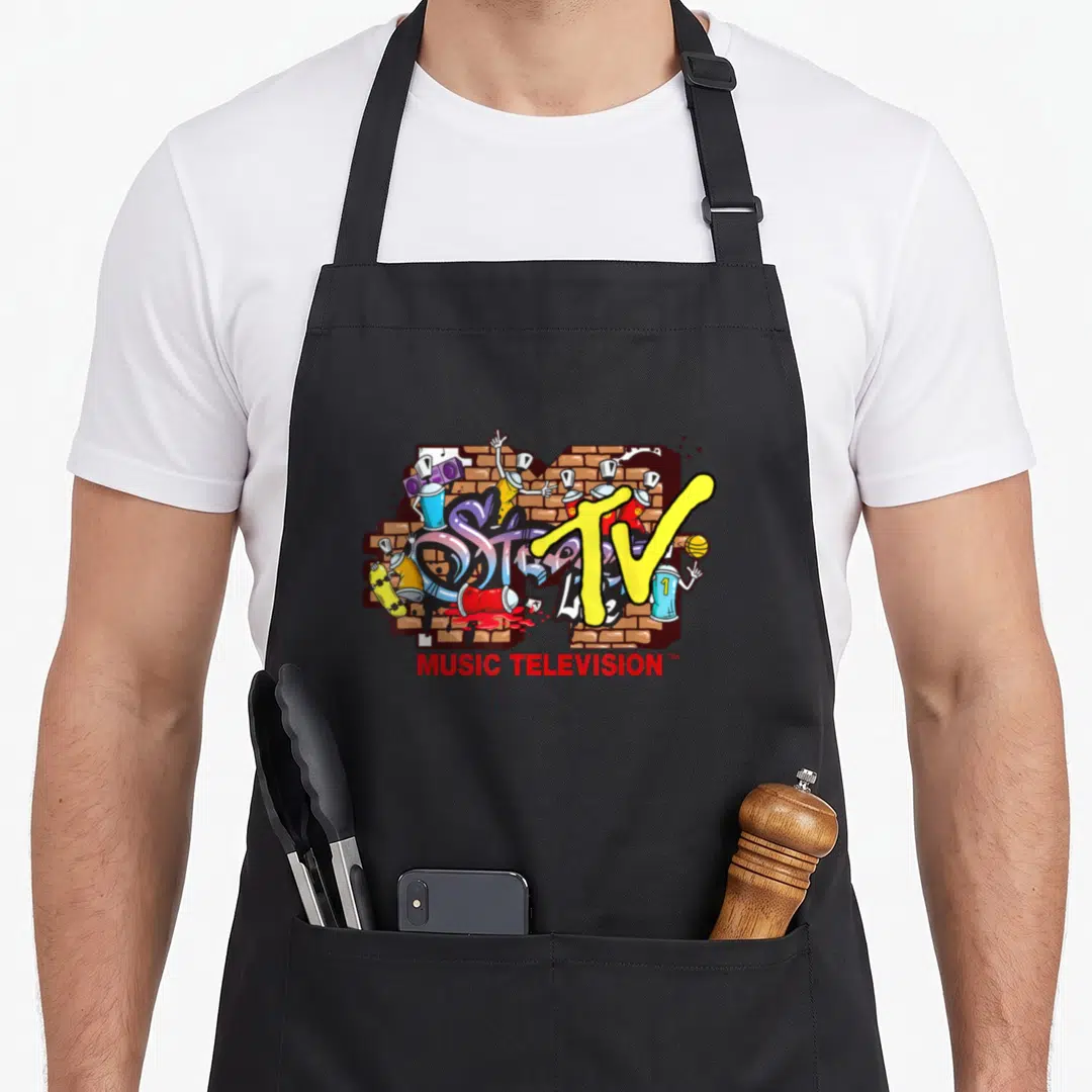 Mtv streetwear apron - Yellow TV logo over brick wall with cartoon spray cans and red MUSIC TELEVISION text — shown on a black cotton canvas apron against a white background