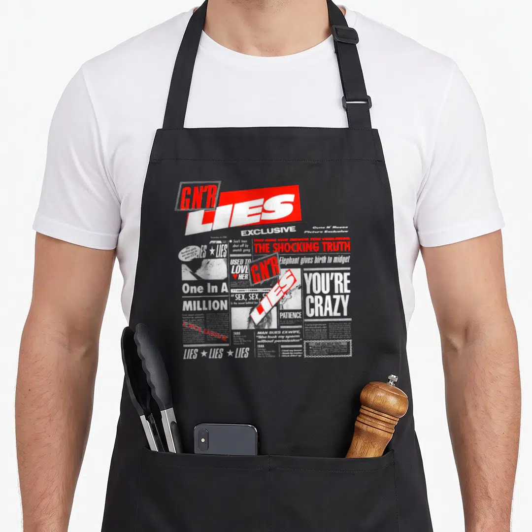 Lie gun apron - GNR Lies newspaper collage with satirical headlines in grey white and red distressed style — shown on a black cotton canvas apron against a white background