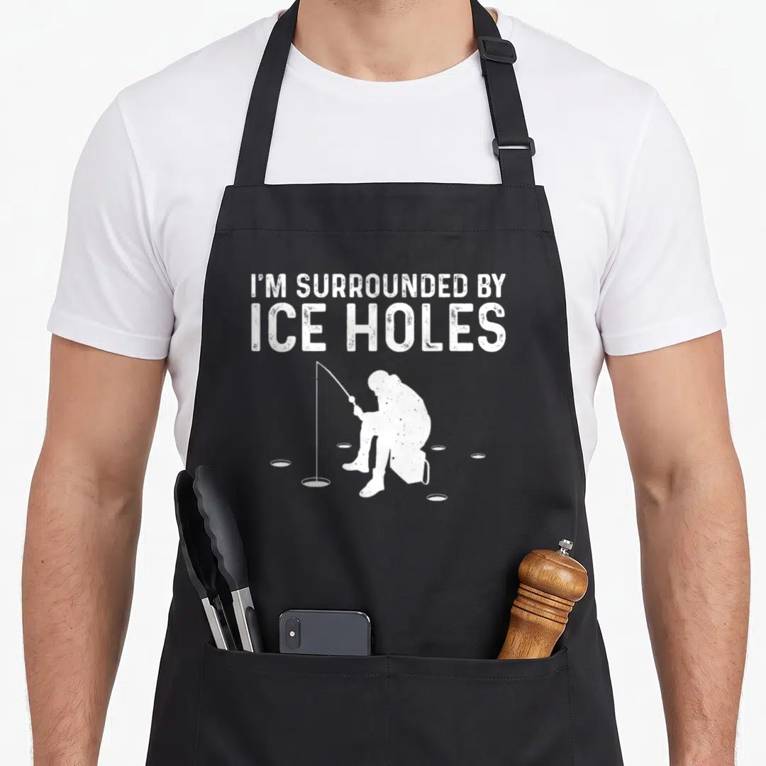Snow fishing aprons - White fisherman silhouette surrounded by ice holes under stacked text — shown on a black cotton canvas apron against a white background
