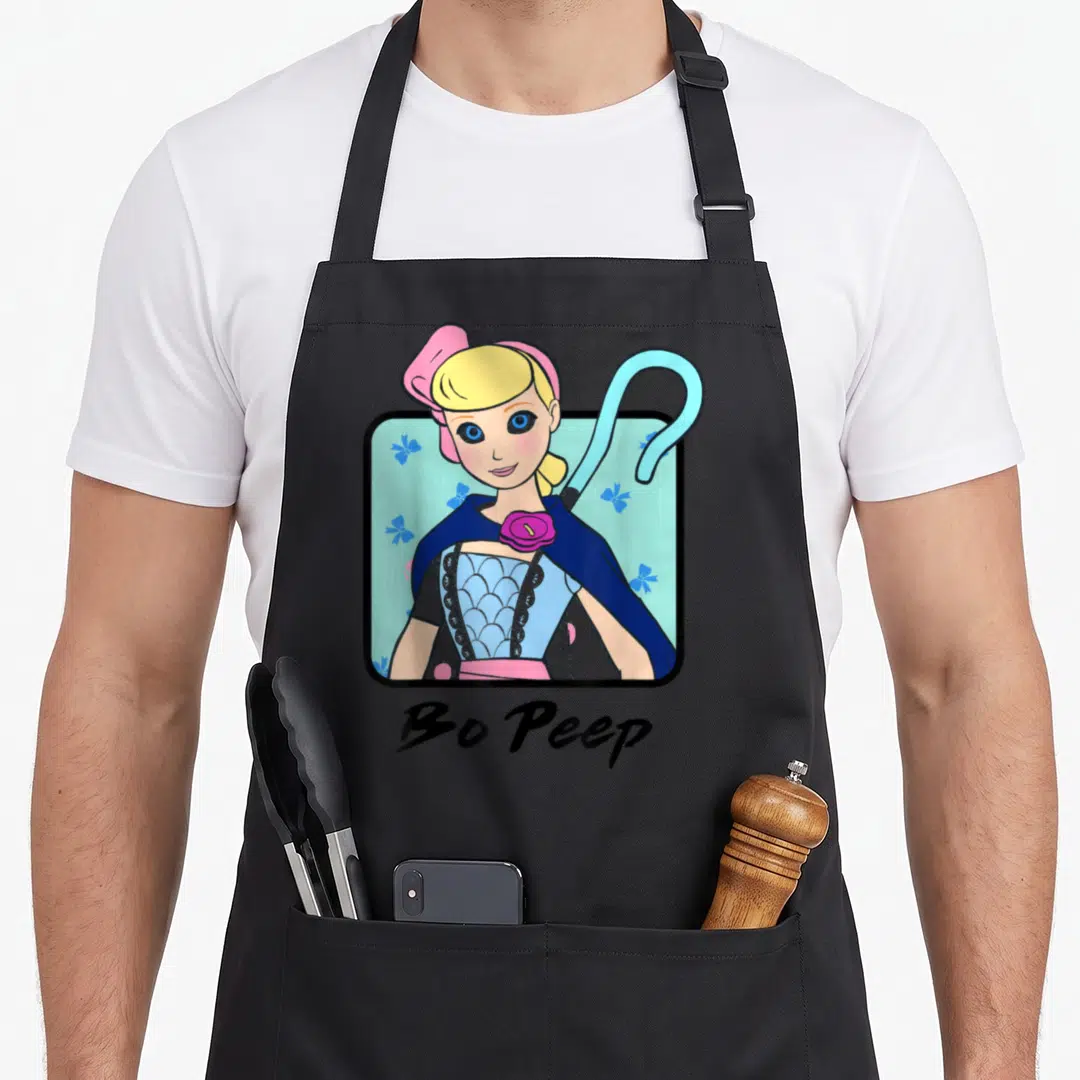 Peep colorful apron - Cartoon Bo Peep portrait with crook in black frame on light blue floral background — shown on a black cotton canvas apron against a white background