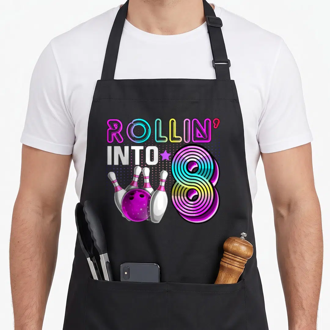 Rollin bowling birthday apron - Neon ROLLIN INTO 8 graphic with bowling ball and four pins in purple blue yellow — shown on a black cotton canvas apron against a white background